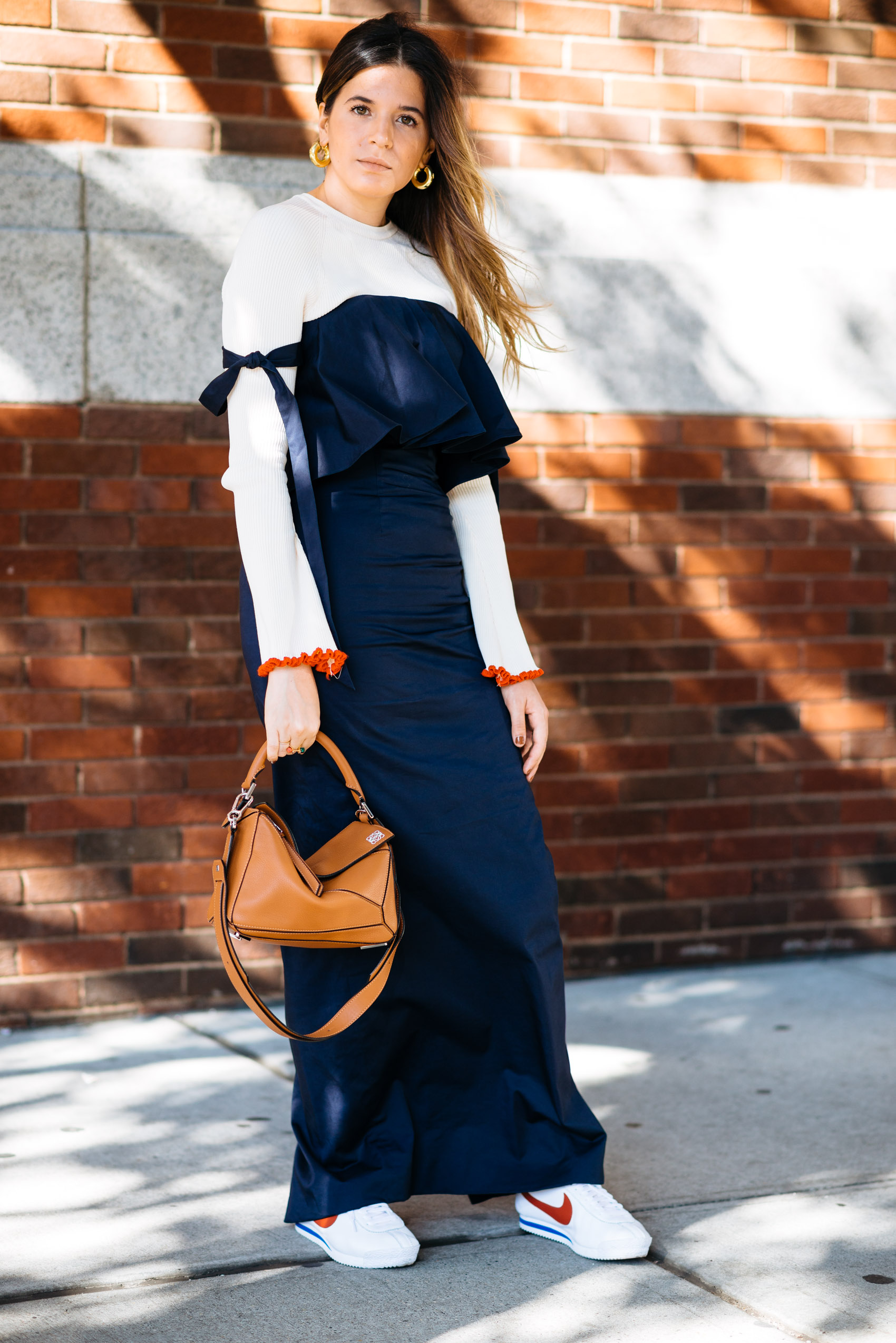 Blogger Maristella wearing an on trend ribbed knit sweater with flared sleeves and contrast trim, statement gold earrings, Nike Classic sneakers and Loewe bag