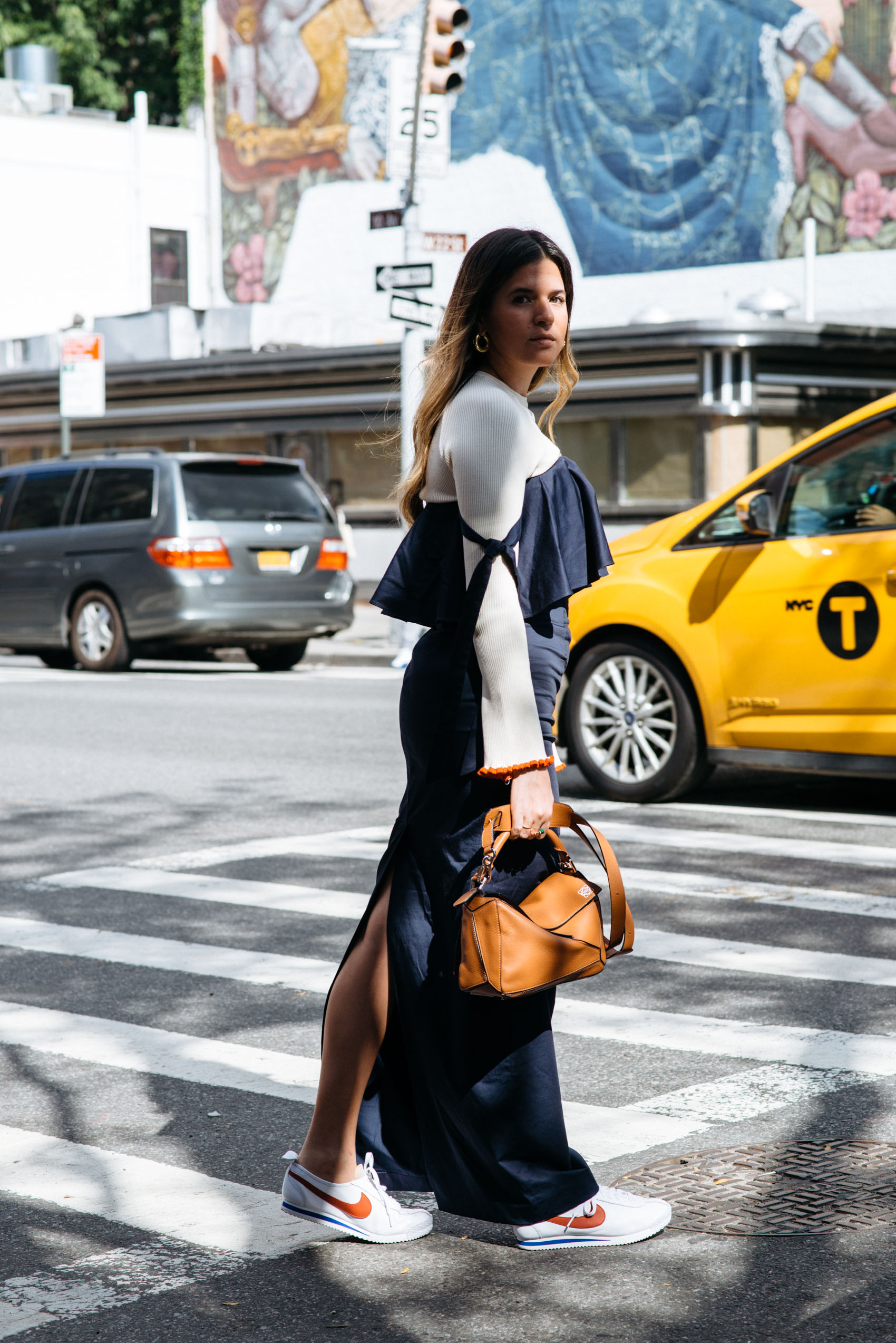 Maristella in a transitional fall outfit idea layering a sweater underneath a column maxi dress, with sneakers and a Loewe bag