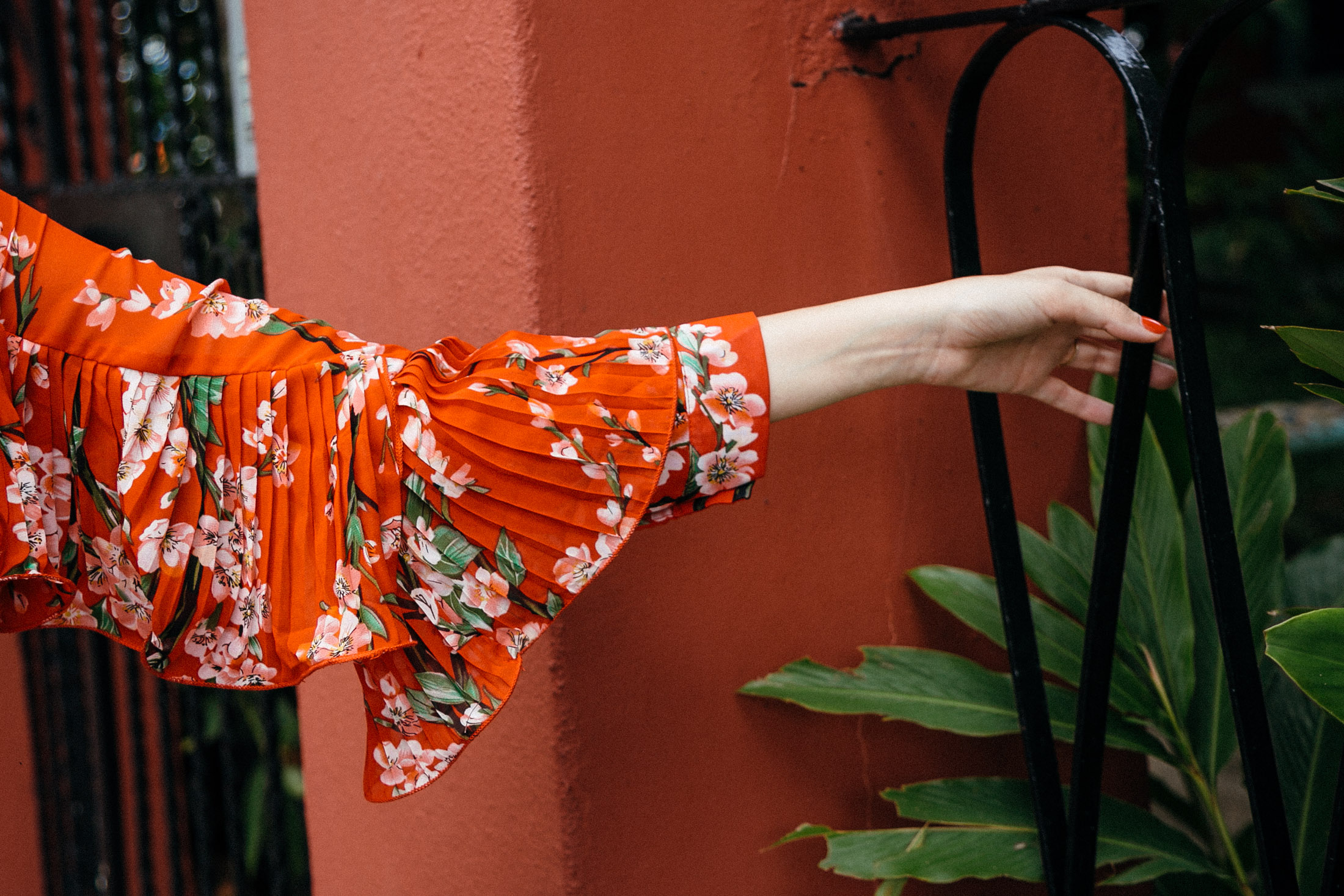 Outfit detail featuring pleated ruffle sleeves on a red floral dress