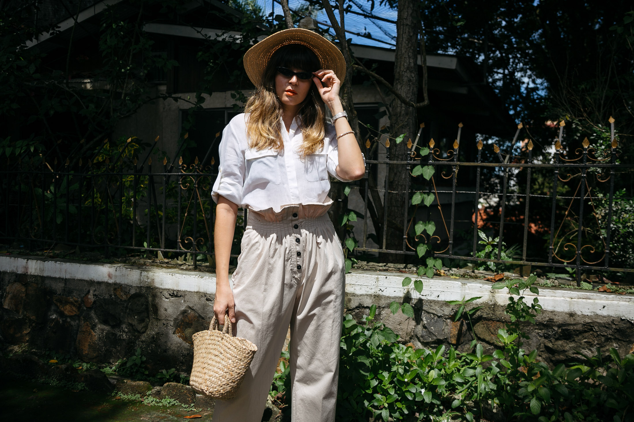 Maristella wears a white linen shirt, khaki paper bag pants, straw hat and suede mules.