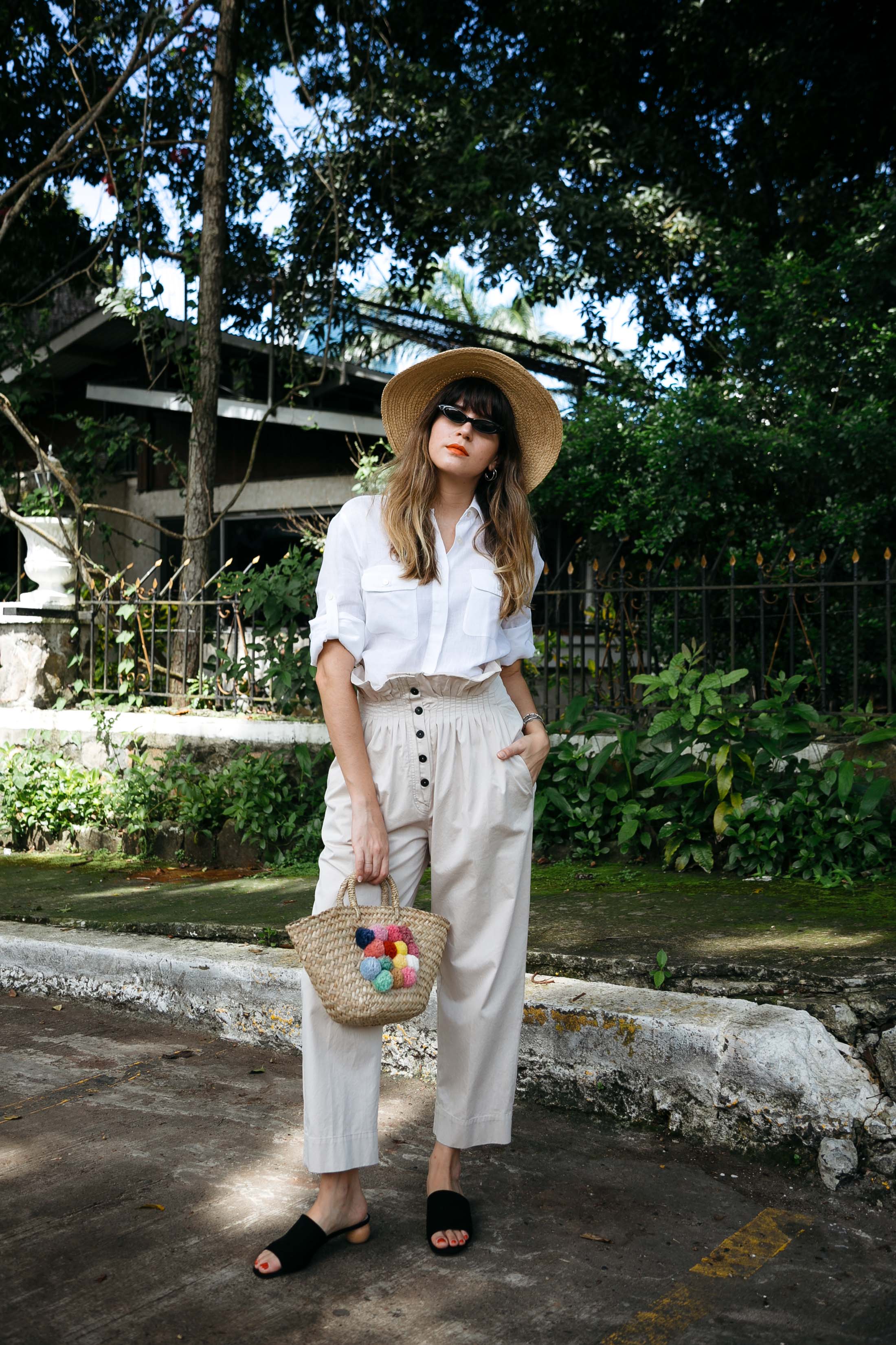 Maristella wears a white linen shirt from Max Mara, Mango khaki trousers, Purificacion Garcia straw bag and matrix style sunglasses from Giant Vintage