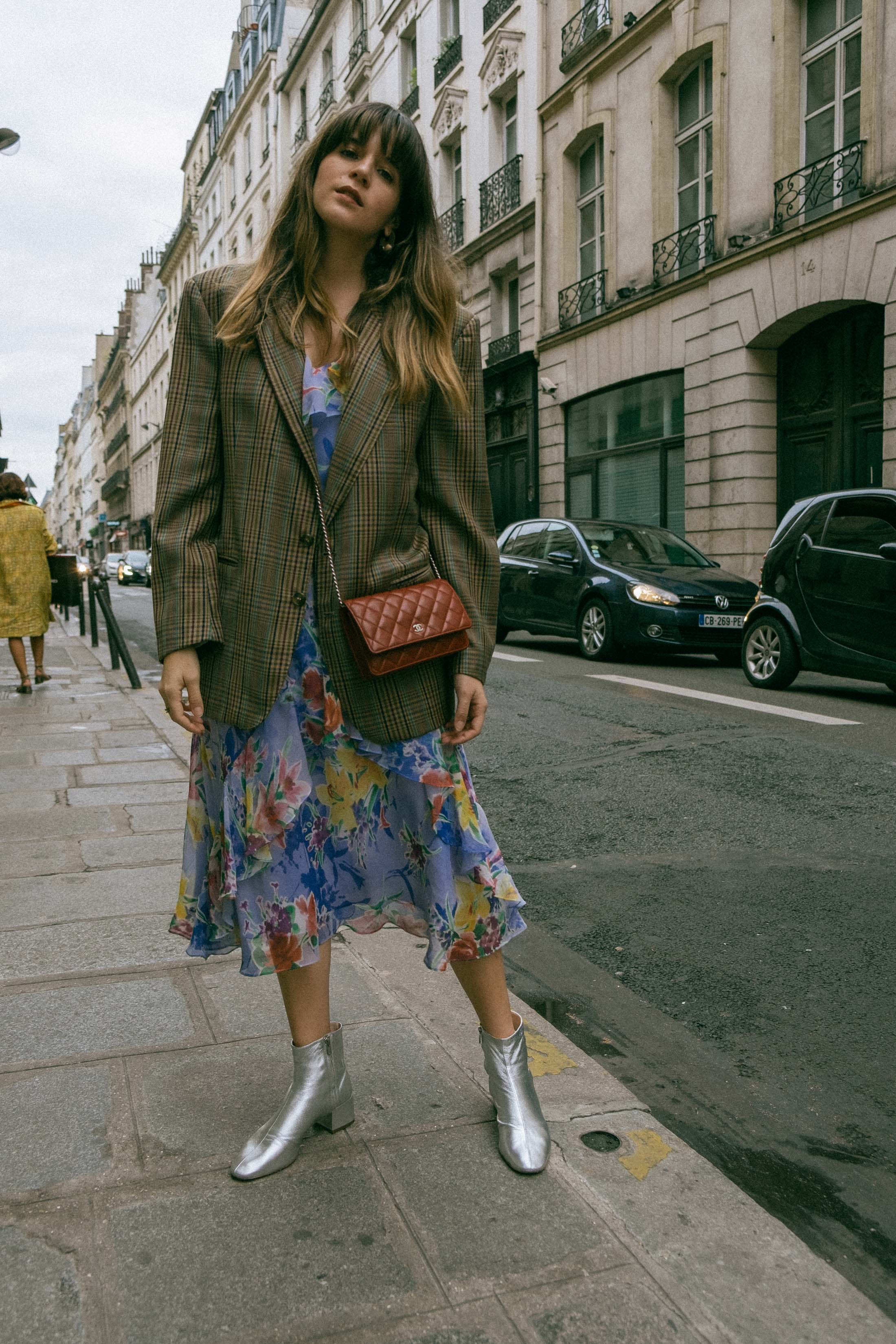 Maristella wears a vintage men's blazer, vintage floral dress, Loeffler Randall silver boots and mini burgundy Chanel crossbody bag in Paris