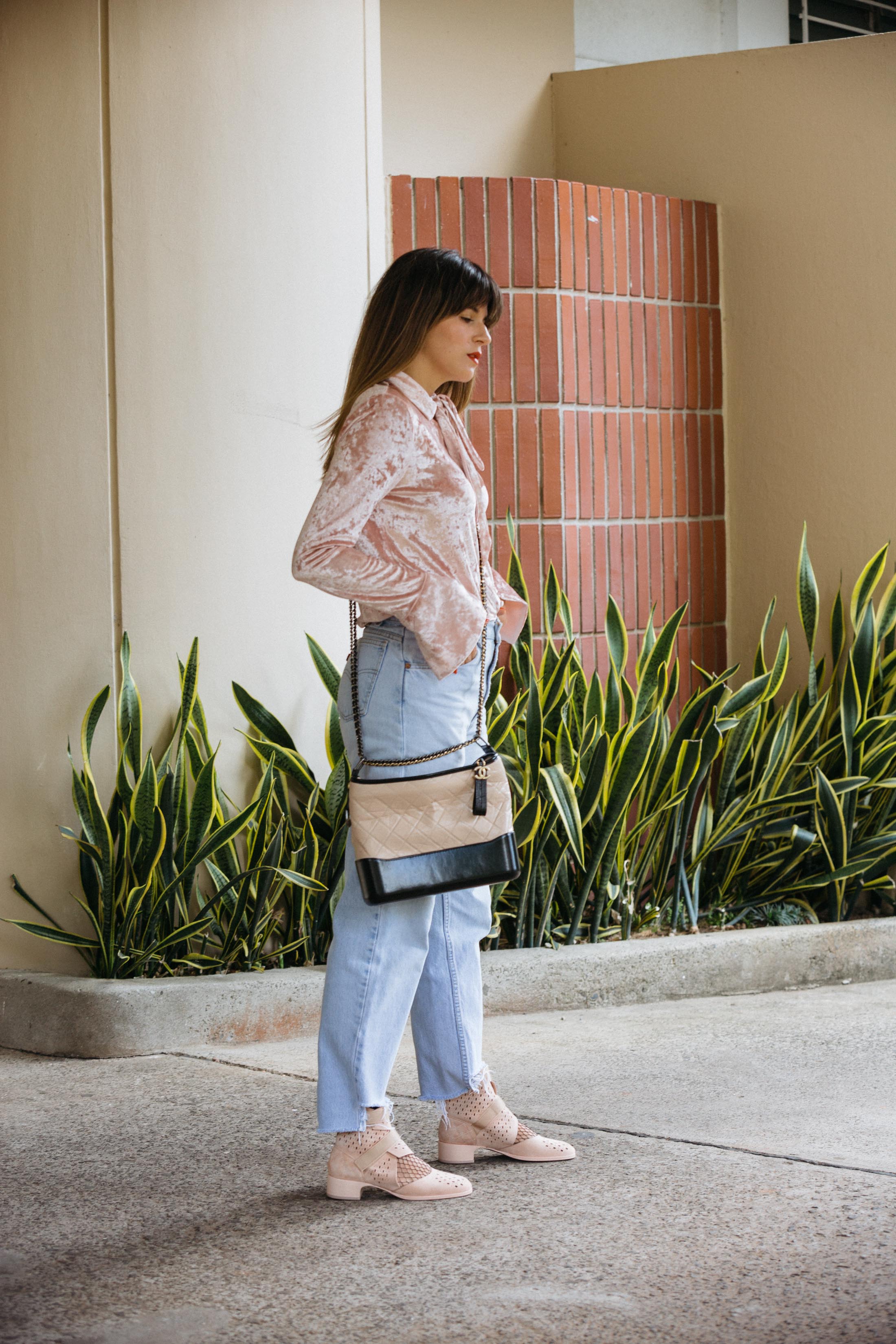 Pink velvet shirt with jeans and long cross body Chanel bag, pink suede Chanel boots with fish net socks