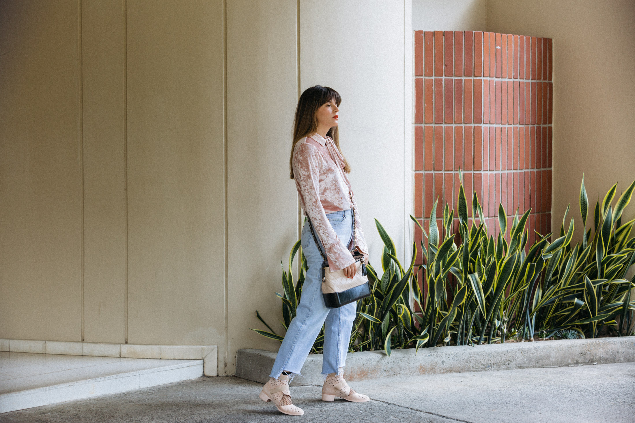 Maristella wears a pink velvet shirt, high low hem jeans, the new Chanel Gabrielle bag, Chanel pink suede perforated boots and fishnet socks