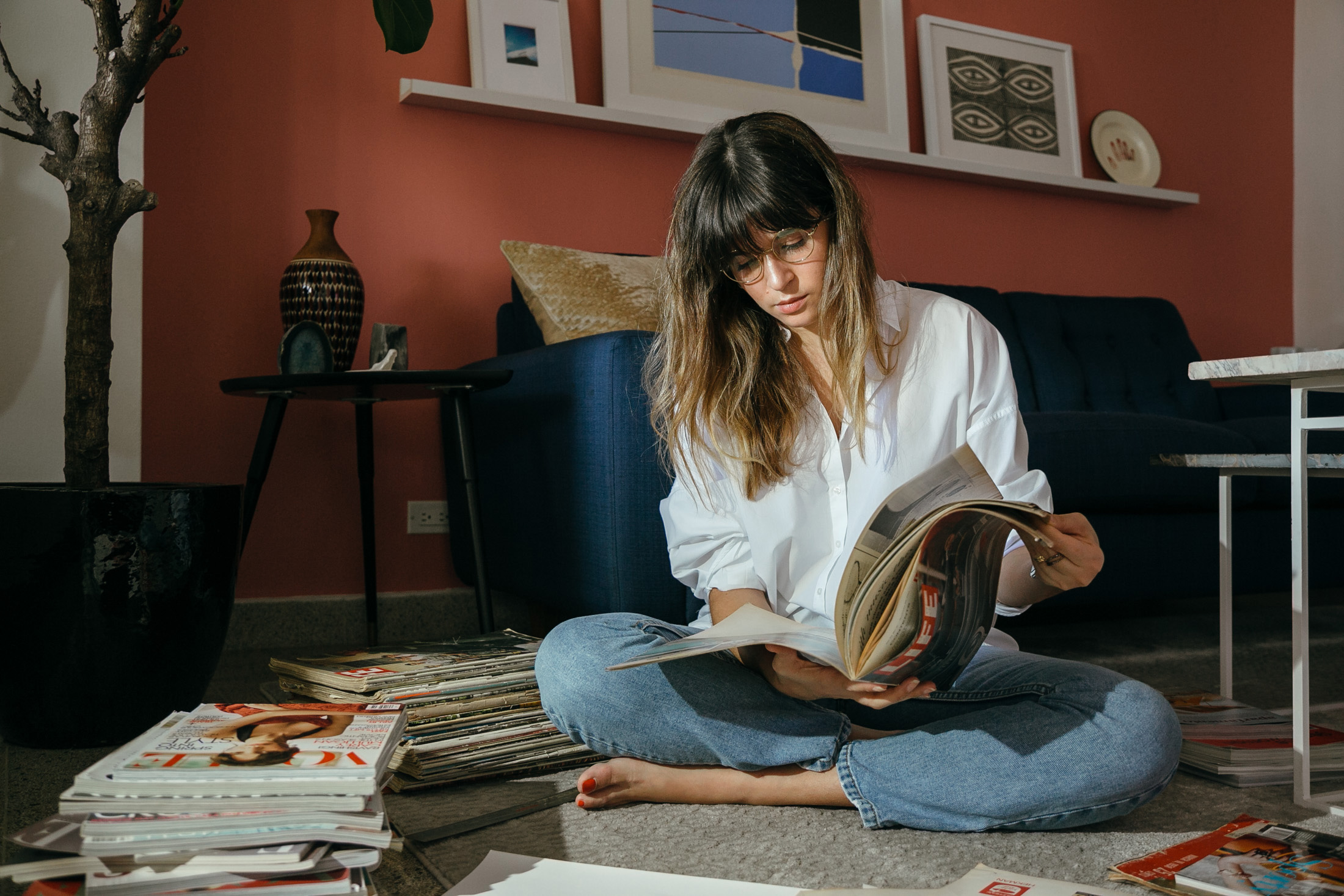 Maristella sits in her living room floor looking through magazines for her collages