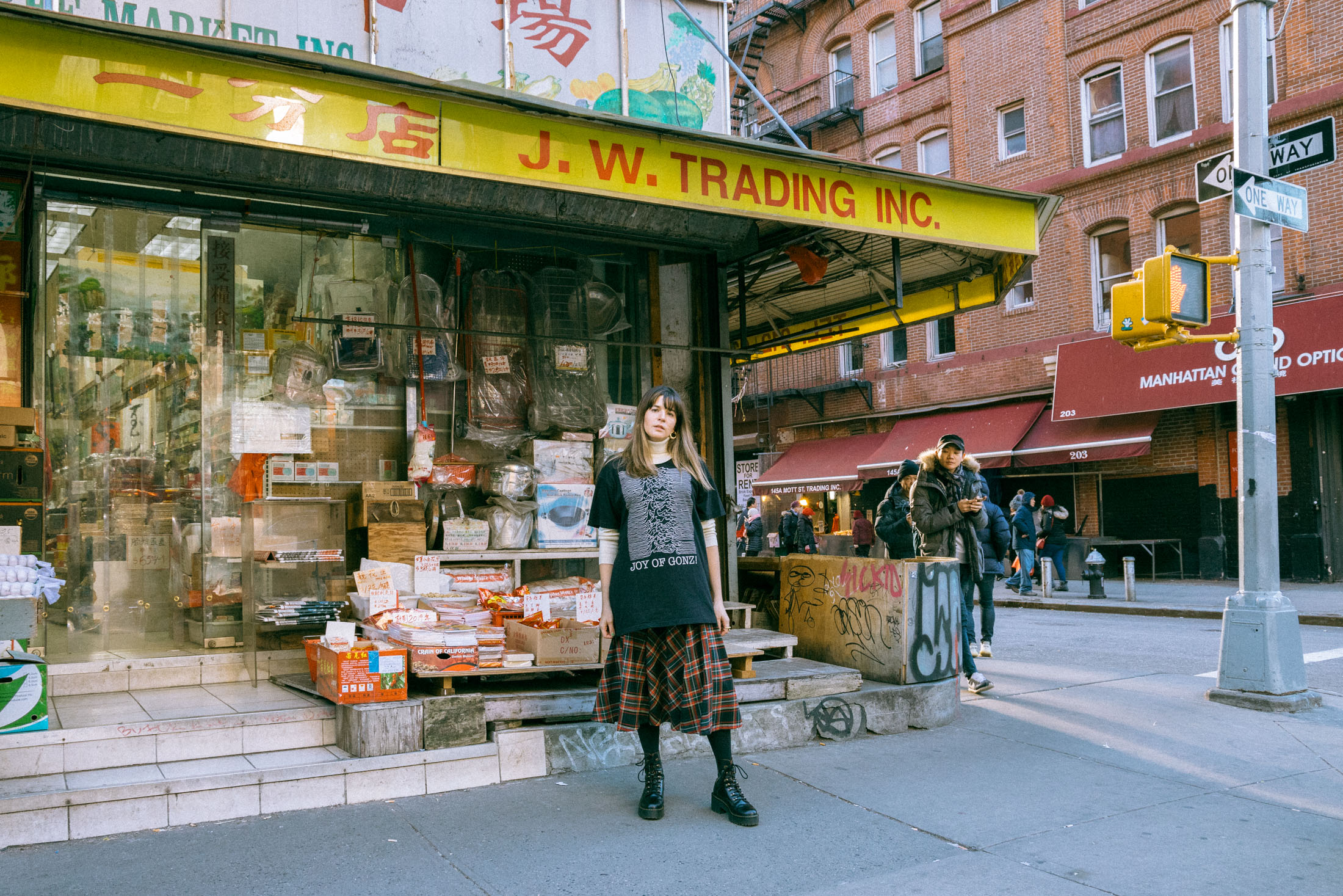 Maristella wears a turtleneck sweater under an oversize t-shirt, tartan skirt from Zara, Dr. Martens boots.