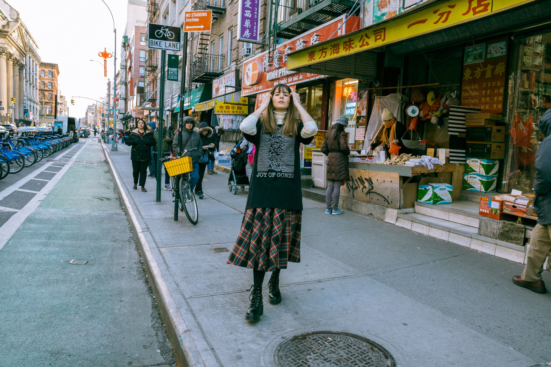 Maristella wears a turtleneck sweater under an oversize t-shirt, tartan skirt from Zara, Dr. Martens boots.