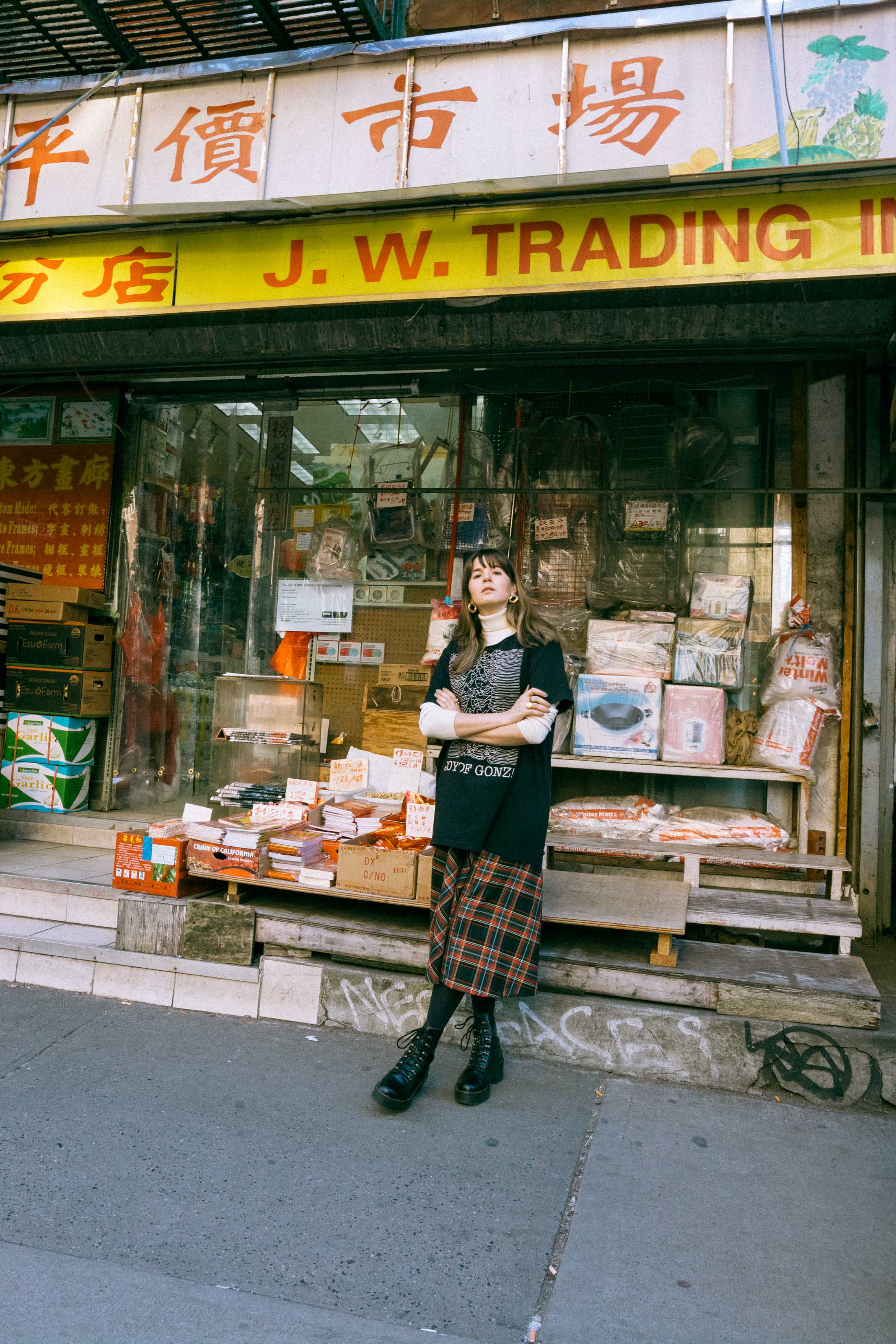 Maristella wears a turtleneck sweater under an oversize t-shirt, tartan skirt from Zara, Dr. Martens boots.