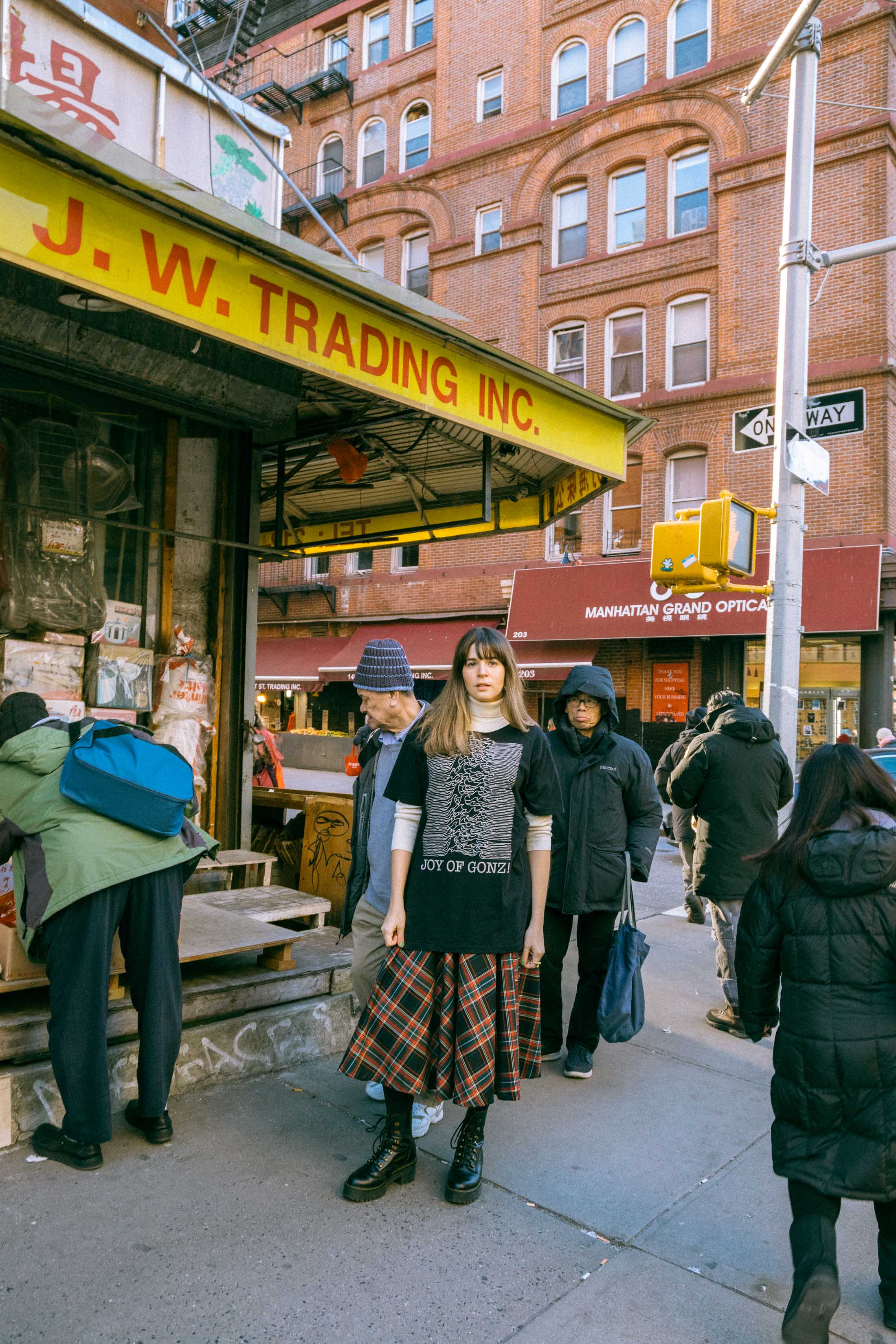 Maristella wears a vintage turtleneck sweater under an oversize black t-shirt, plaid midi skirt from Zara, Dr. Martens boots.