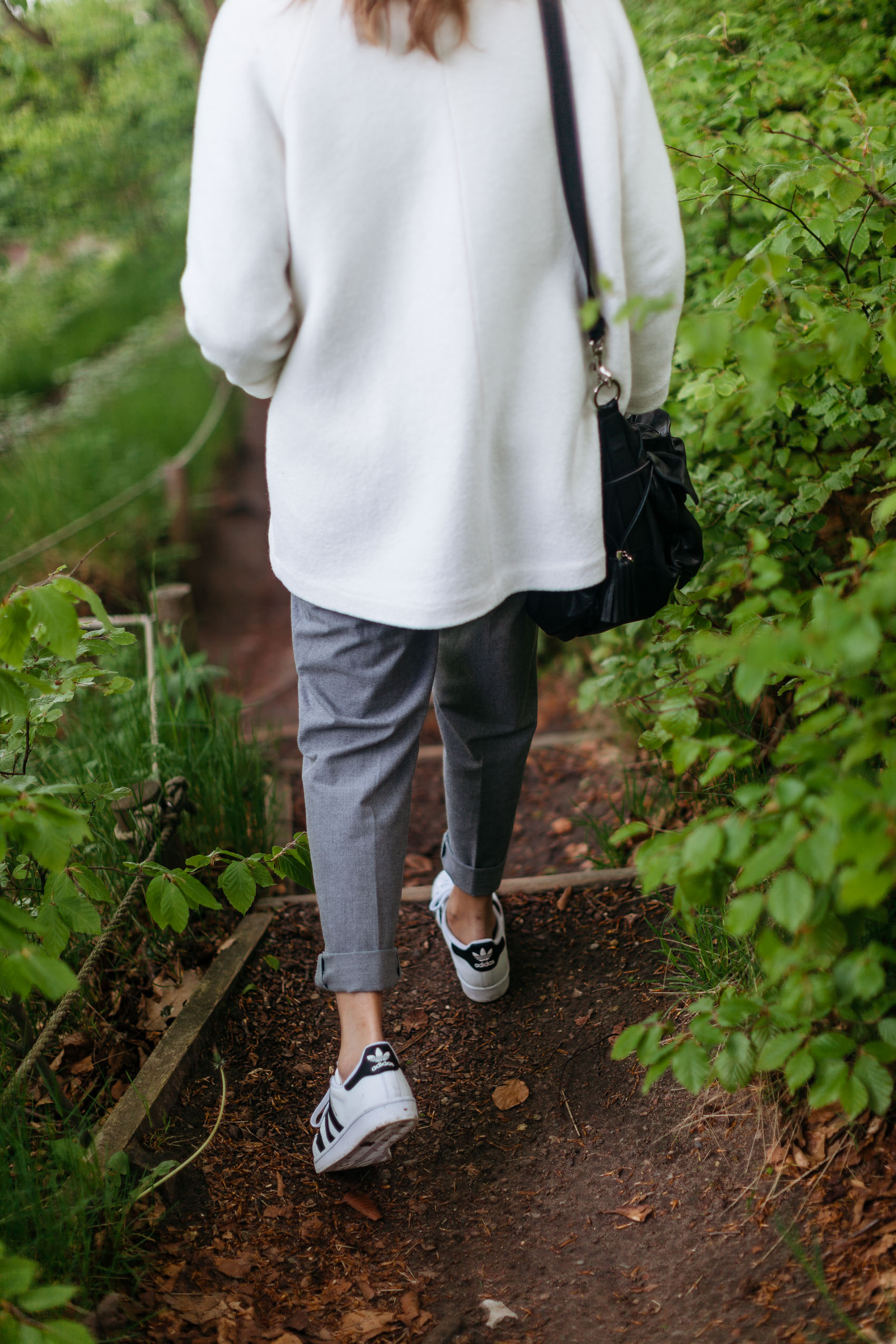 Maristella wearing a white coat, grey trousers, adidas Superstar sneakers and Loewe Flamenco Bucket bag